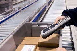 Worker scanning boxes in assembly line