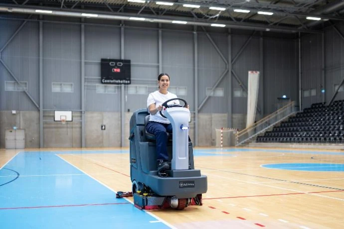 Ride-on floor scrubber operating inside a sports venue