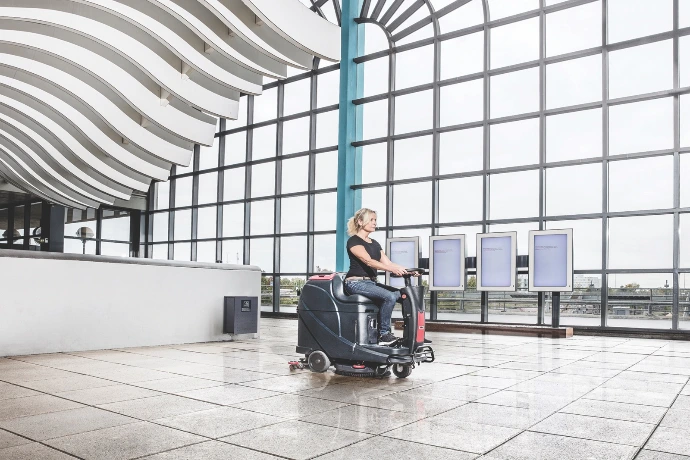 Ride-on scrubber cleaning the floor inside a public community building