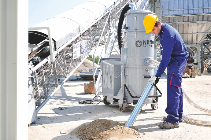 Operator using an industrial vacuum system for dust extraction in a mining processing area